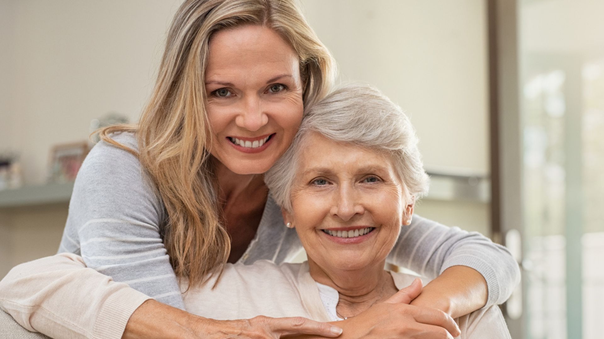 A cheerful woman with blond hair with arms around a happy elderly woman. Senior home care in Pleasant Hill