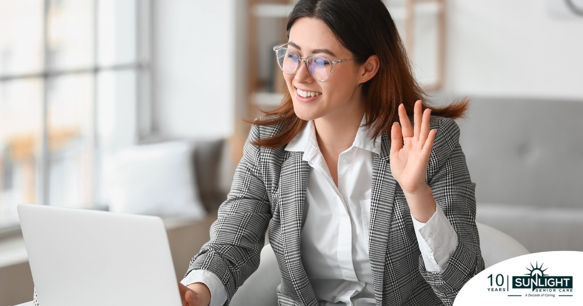 A well-dressed woman smiles and says hi on a videoconference, representing a candidate who is well-prepared for a caregiver interview.