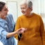 A caregiver helps a client get around, demonstrating one of the job duties of a caregiver.