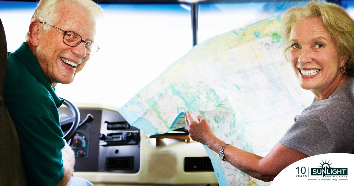 An older couple looks back smiling from the front of an RV, representing how day trips for seniors can help boost the mood of everyone.