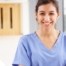 A woman in scrubs smiles, representing the good results that can come when caregivers branch out to become CNAs.
