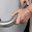 An older adult uses a grab bar representing one of the home modifications that is helpful for fall prevention for elderly adults.