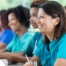 Several students in scrubs happily attend a class, representing caregiver training.