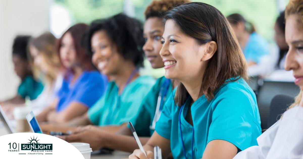 Several students in scrubs happily attend a class, representing caregiver training.