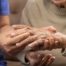 A care provider examines an older adult’s fingers, representing what would happen in an examination for rheumatoid arthritis.