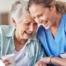 A woman in scrubs laughs with a senior woman, representing how caregiving can be a great career choice.